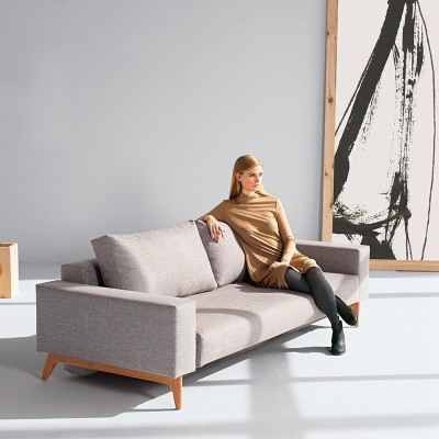 Chica sentada en Sofá cama Idun color gris 521 de Innovation Living Chica sentada en Sofá cama Idun color gris 521 de Innovation Living